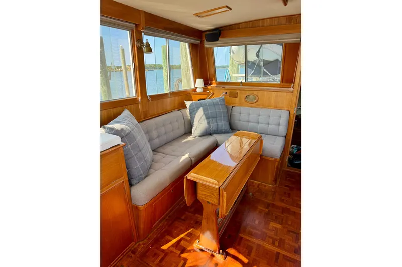 Slide: The Image of 1990 Grand Banks 36 Classic yacht helm with wooden wheel and seating, on calm water. - 36