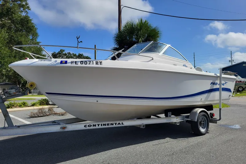 The Image of 2004 Pro-Line 20 DC boat on trailer, parked outdoors under a clear blue sky. - 1