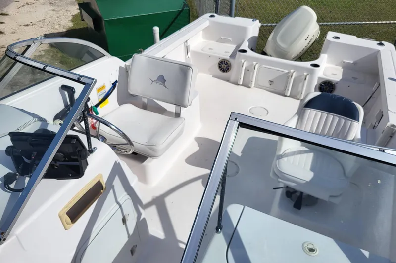 Slide: The Image of 2004 Pro-Line 20 DC boat interior with seating and steering wheel, docked outdoors. - 9