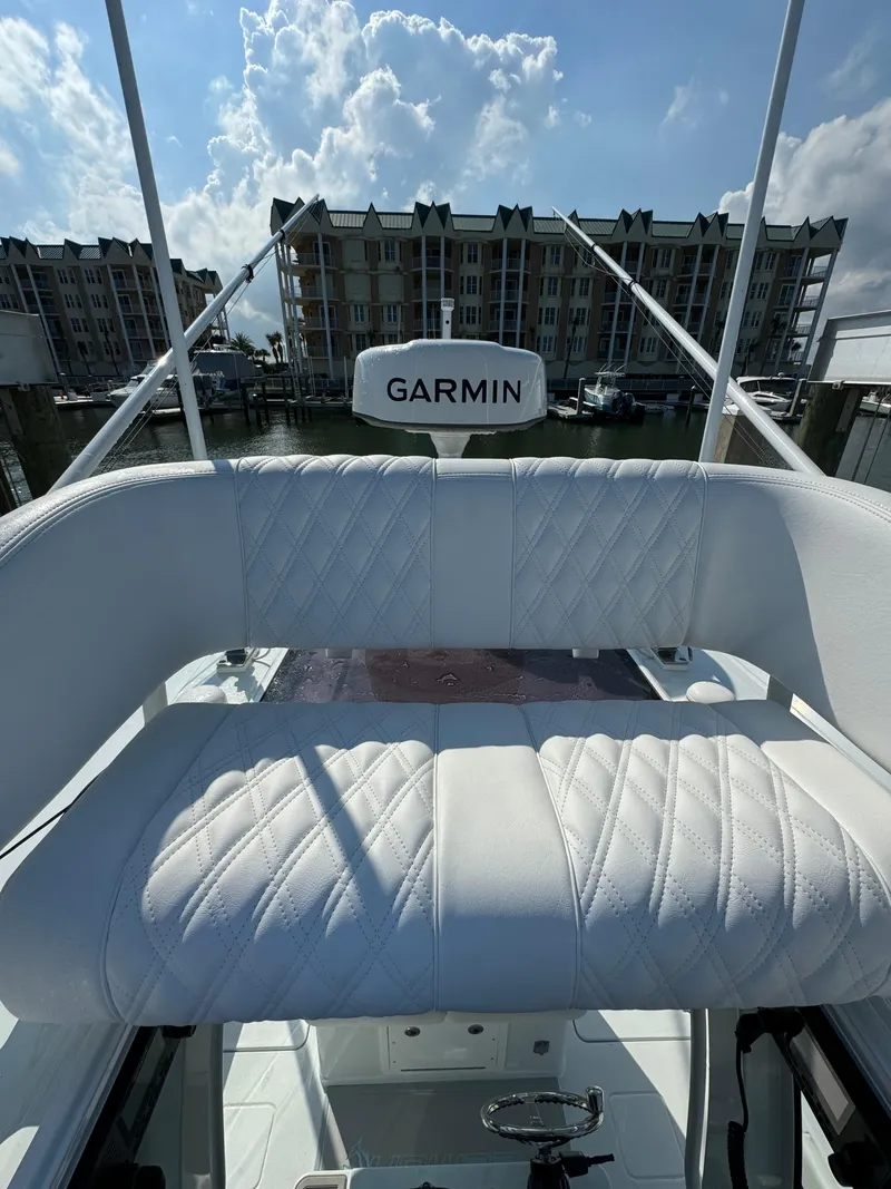 Slide: The Image of 2025 Freeman 28 boat with Garmin equipment, featuring white cushioned seating, docked near waterfront buildings. - 20