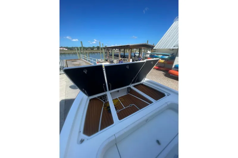 Slide: The Image of 2015 Barker Boatworks 26 Bay deck view at marina, showcasing sleek design and storage compartments. - 7