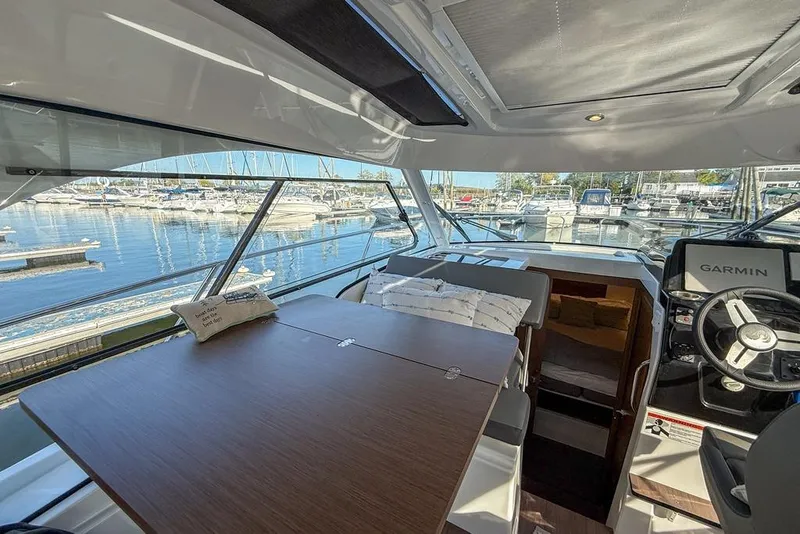 Slide: The Image of Interior of 2024 Beneteau Antares 9 boat with table and helm, docked at marina. - 6