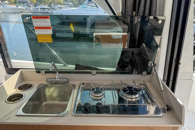 Slide: The Image of 2024 Beneteau Antares 9 boat kitchen with sink and dual-burner stove. - 8