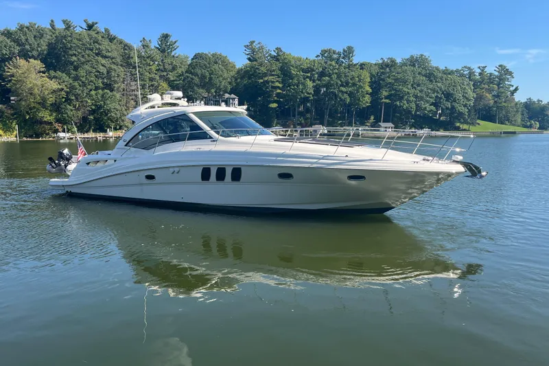 Slide: The Image of 2009 Sea Ray 48 Sundancer yacht on a serene lake with lush green trees. - 2