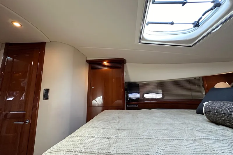 Slide: The Image of 2009 Sea Ray 48 Sundancer cabin interior with skylight, wooden cabinetry, and comfortable bedding. - 27