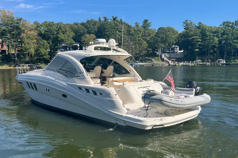 Slide: The Image of 2009 Sea Ray 48 Sundancer yacht on a serene lake with lush green surroundings. - 4