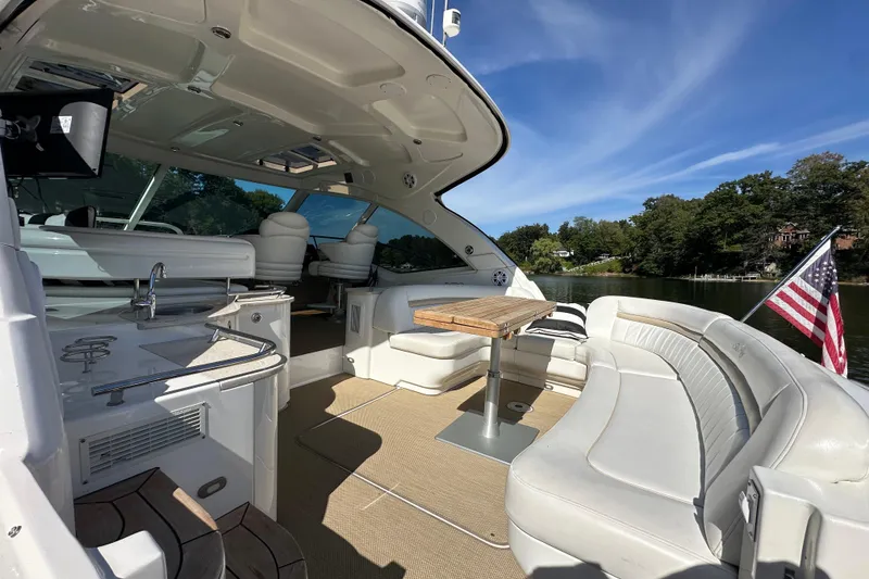 Slide: The Image of 2009 Sea Ray 48 Sundancer yacht interior with seating, table, and American flag on a sunny day. - 6