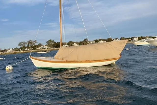 Slide: The Image of 1980 Buzzards Bay sloop with covered sails on calm water near shoreline. - 2