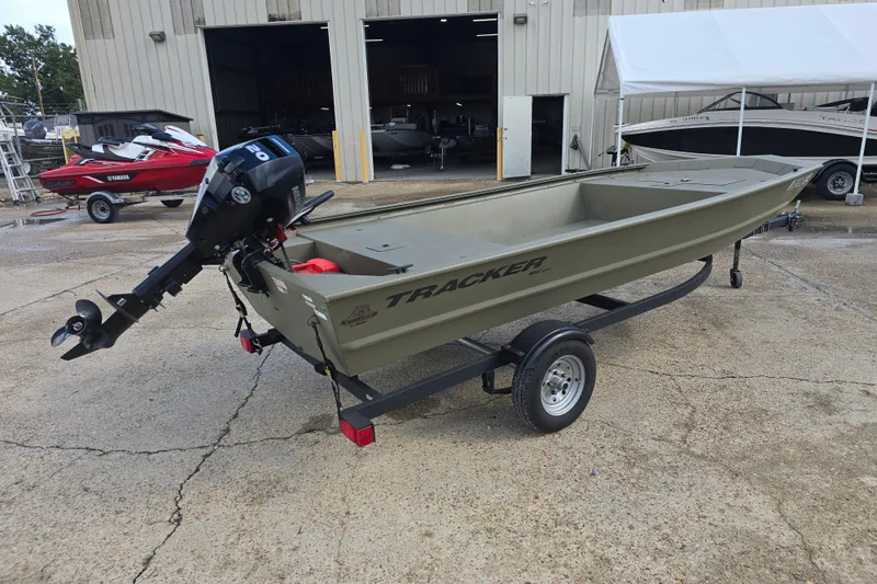 Slide: The Image of 2024 Tracker Grizzly 1648 Jon boat on trailer, parked outside a warehouse. - 3
