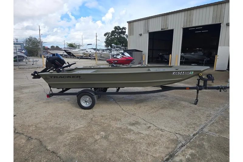 Slide: The Image of 2024 Tracker Grizzly 1648 Jon boat on trailer, parked outside a warehouse. - 4
