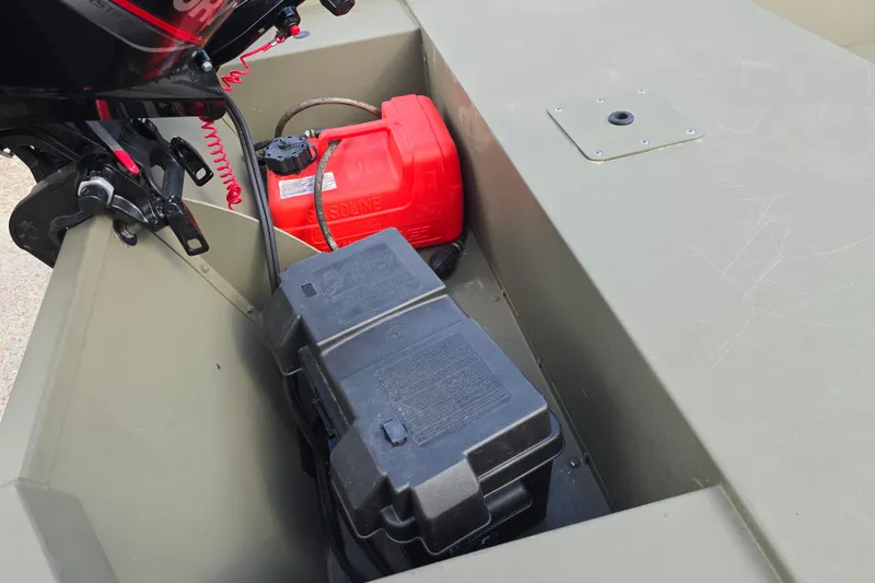 Slide: The Image of 2024 Tracker Grizzly 1648 Jon boat interior with motor, fuel tank, and battery compartment. - 8