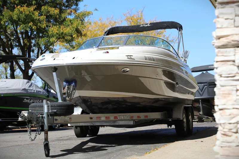 Slide: The Image of 2008 Sea Ray 220 Sundeck boat on trailer, parked outdoors with trees in background. - 15