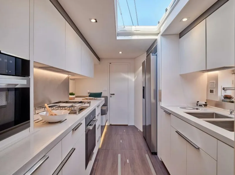 Slide: The Image of Modern kitchen interior in 2021 Lagoon Seventy 7 yacht, featuring sleek white cabinetry and stainless steel appliances. - 6