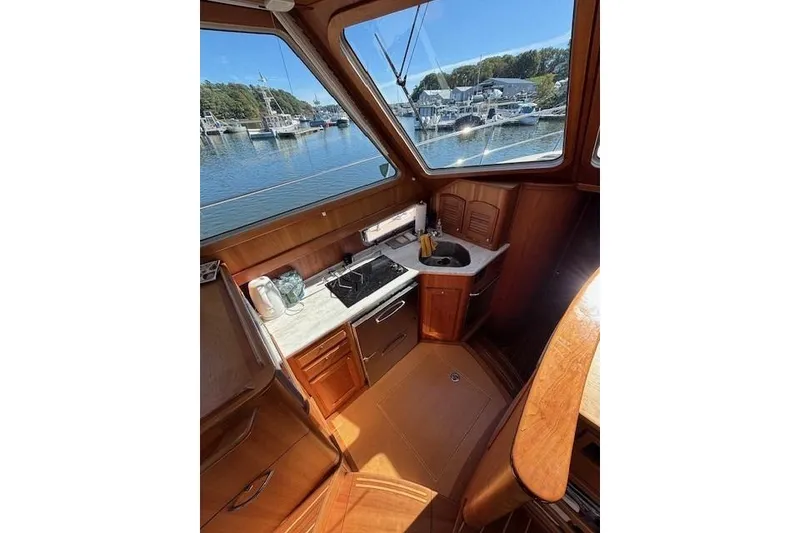 Slide: The Image of 2012 Sabre 42 Salon Express interior with kitchenette, featuring wood cabinetry and marina view. - 11
