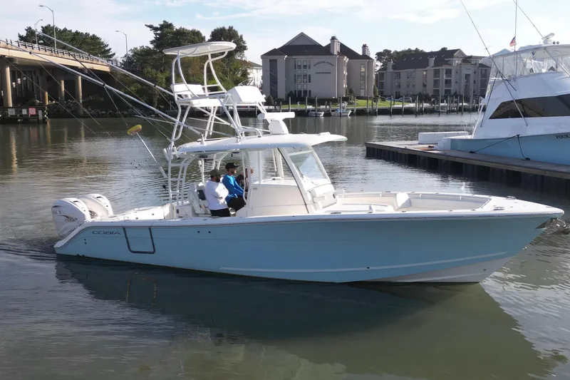 The Image of 2020 Cobia 350 Center Console boat cruising in a marina with two passengers. - 0
