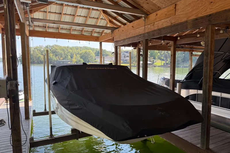 Slide: The Image of 2022 MasterCraft NXT24 boat covered and docked in a lakeside boathouse. - 10