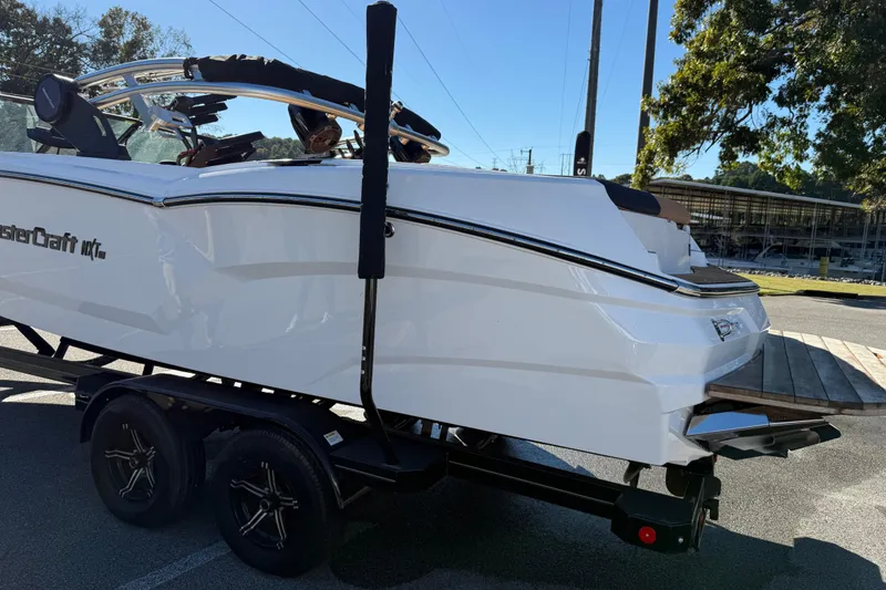 Slide: The Image of 2022 MasterCraft NXT24 boat on trailer, parked outdoors in sunny setting. - 19