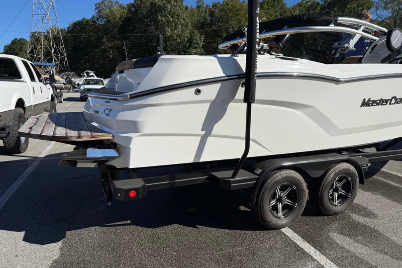 Slide: The Image of 2022 MasterCraft NXT24 boat on trailer in parking lot, side view. - 20