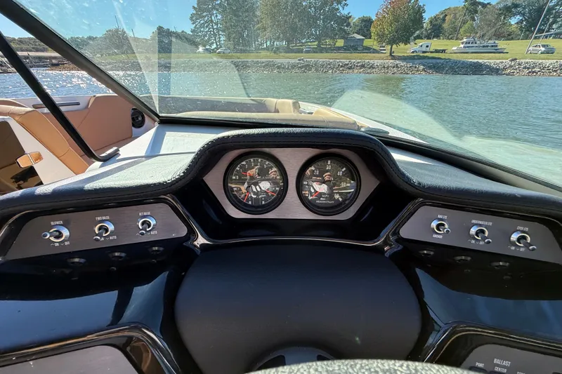 Slide: The Image of 2022 MasterCraft NXT24 dashboard with gauges and controls, overlooking a scenic lake view. - 34