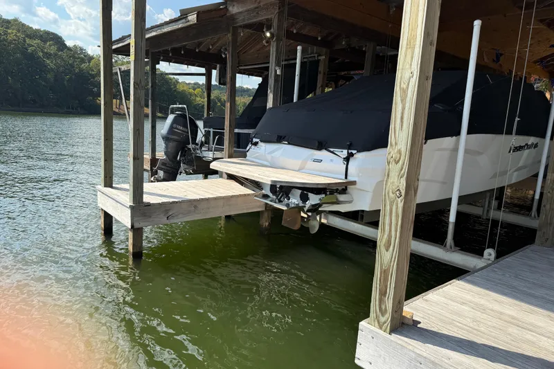 Slide: The Image of 2022 MasterCraft NXT24 boat covered in black tarp, docked in a wooden boathouse. - 4