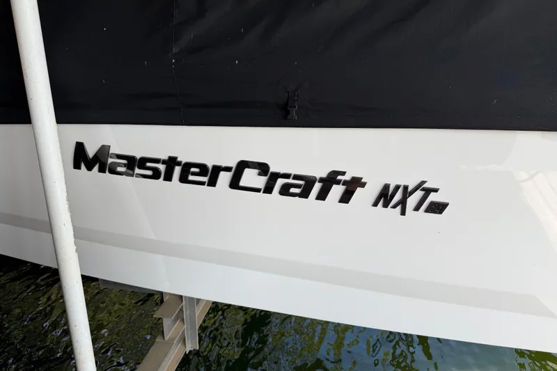 Slide: The Image of 2022 MasterCraft NXT24 boat with cover, docked near wooden pier. - 7
