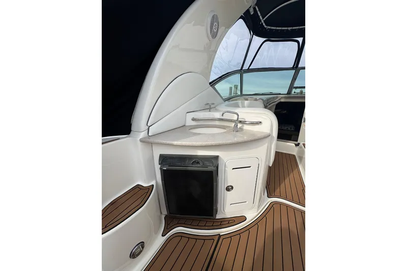 Slide: The Image of 2007 Sea Ray 320 Sundancer interior with sink and mini fridge on teak flooring. - 12