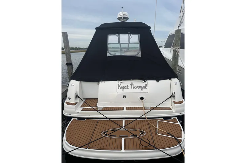 Slide: The Image of 2007 Sea Ray 320 Sundancer docked, featuring a black canvas cover and teak swim platform. - 2