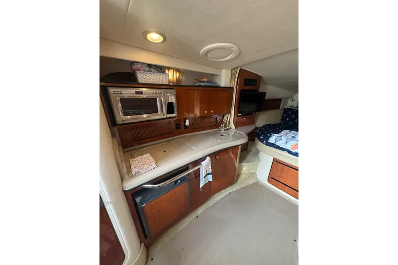 Slide: The Image of 2007 Sea Ray 320 Sundancer interior with kitchenette, microwave, and cozy sleeping area. - 23