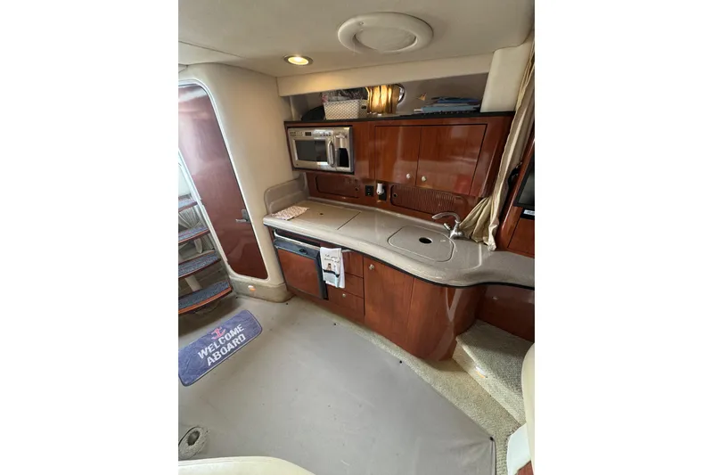 Slide: The Image of 2007 Sea Ray 320 Sundancer interior kitchen with wood cabinets and modern appliances. - 24