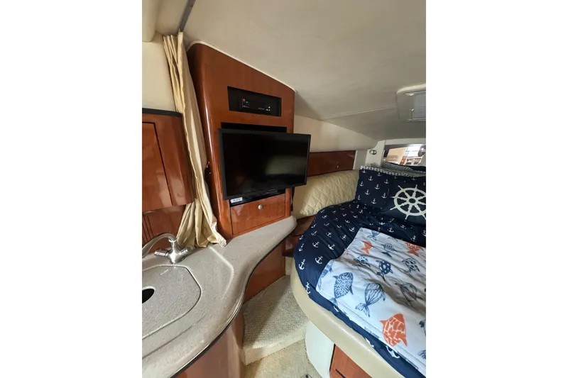 Slide: The Image of 2007 Sea Ray 320 Sundancer cabin interior with TV, sink, and nautical-themed bedding. - 26