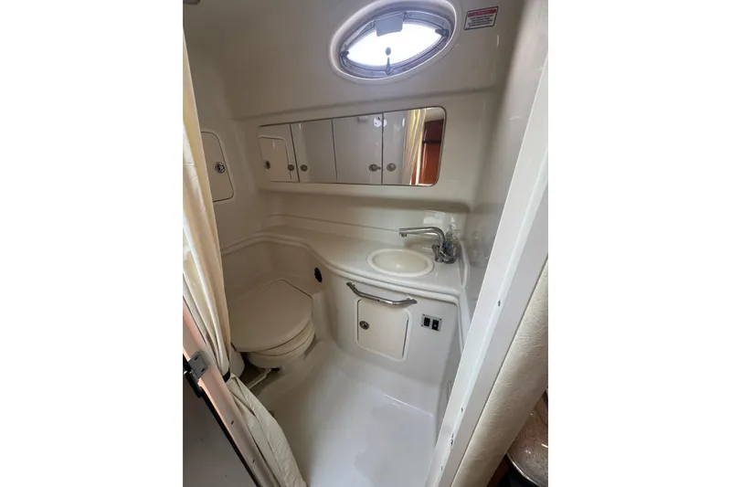Slide: The Image of Compact bathroom in 2007 Sea Ray 320 Sundancer yacht, featuring sink, toilet, and storage cabinets. - 32