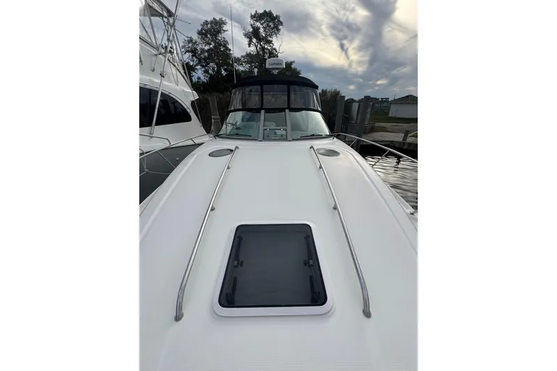 Slide: The Image of 2007 Sea Ray 320 Sundancer yacht deck with hatch, docked under cloudy sky. - 4