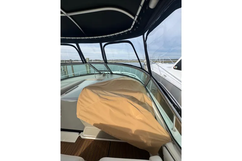 Slide: The Image of 2007 Sea Ray 320 Sundancer boat interior with covered seating, docked by the water. - 5