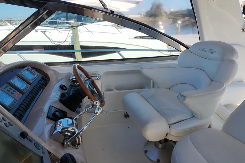 Slide: The Image of Captain's seat and helm of 2002 Sea Ray 410 Sundancer yacht, featuring navigation controls. - 13