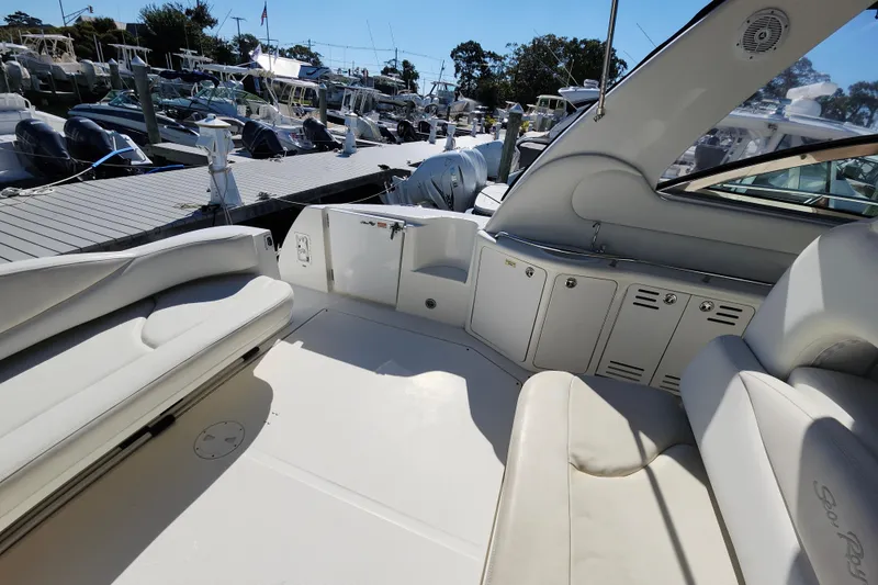 Slide: The Image of 2002 Sea Ray 410 Sundancer yacht interior with white seating and docked boats in background. - 26