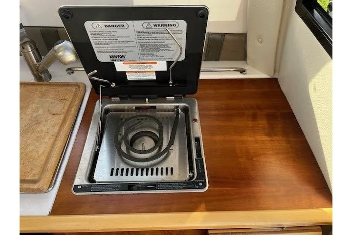 Slide: The Image of 2020 Cutwater C-24 Coupe kitchen with a built-in Kenyon stove on a wooden countertop. - 25