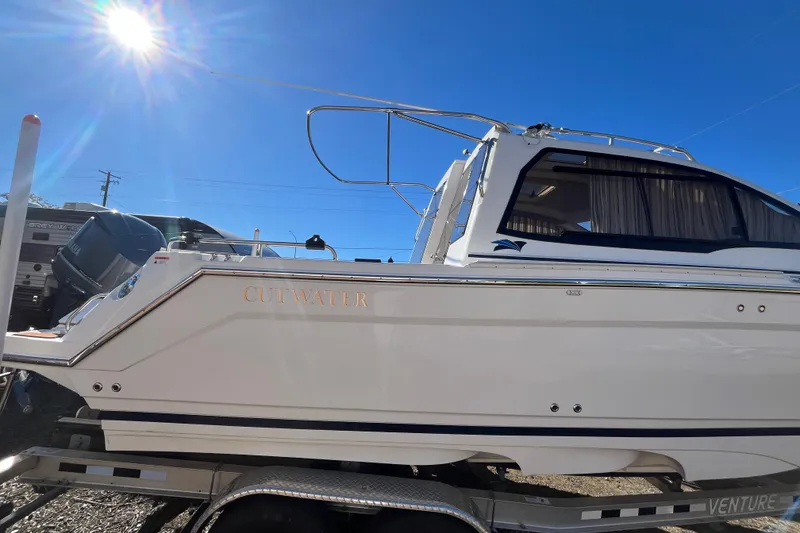 Slide: The Image of 2020 Cutwater C-24 Coupe boat on trailer under bright blue sky. - 3