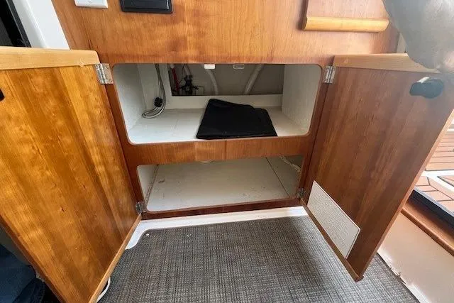 Slide: The Image of 2020 Cutwater C-24 Coupe interior storage with open wooden cabinets and carpeted floor. - 33