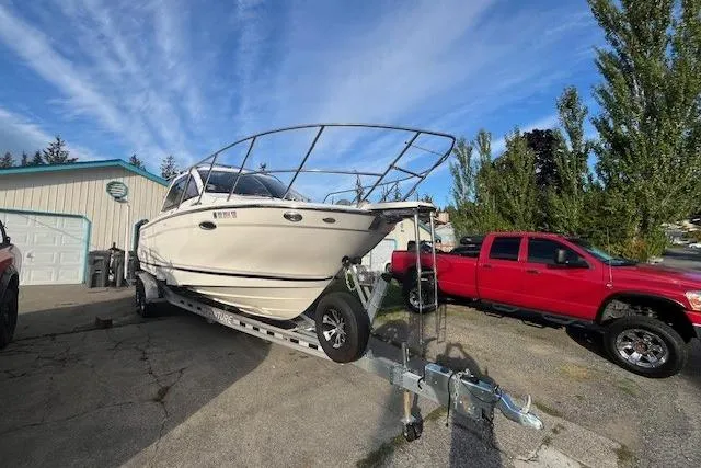 Slide: The Image of 2020 Cutwater C-24 Coupe boat on trailer beside red truck, parked outdoors. - 4