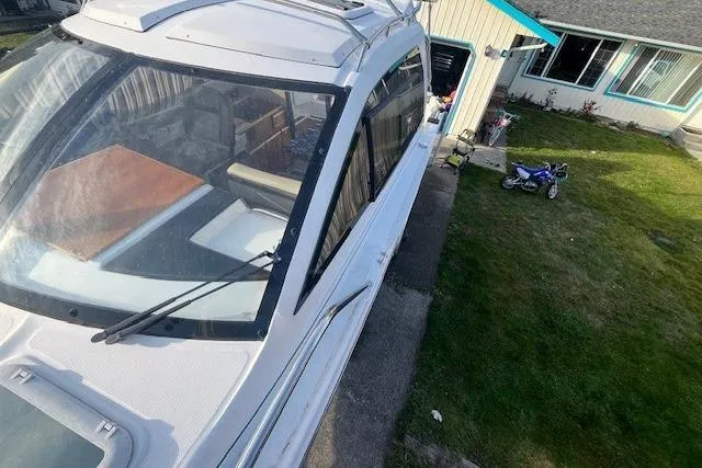 Slide: The Image of 2020 Cutwater C-24 Coupe boat parked beside a house with a small motorcycle nearby. - 8