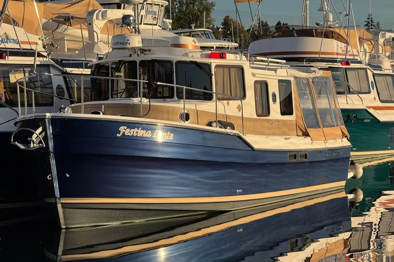 The Image of 2019 Ranger Tugs R-31 S docked near a waterfront building, reflecting on calm water. - 0