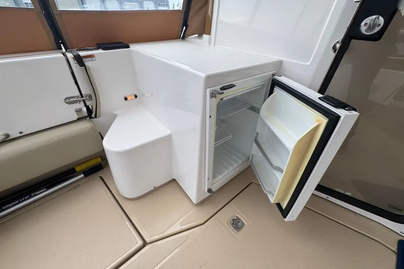 Slide: The Image of 2019 Ranger Tugs R-31 S interior with open mini fridge and beige flooring. - 28