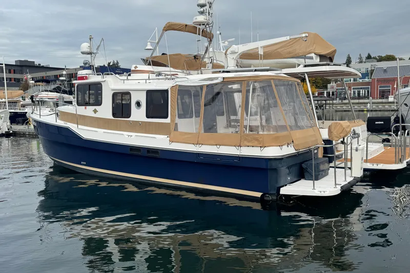 Slide: The Image of 2019 Ranger Tugs R-31 S boat docked in a marina, featuring a blue hull and tan canopy. - 48