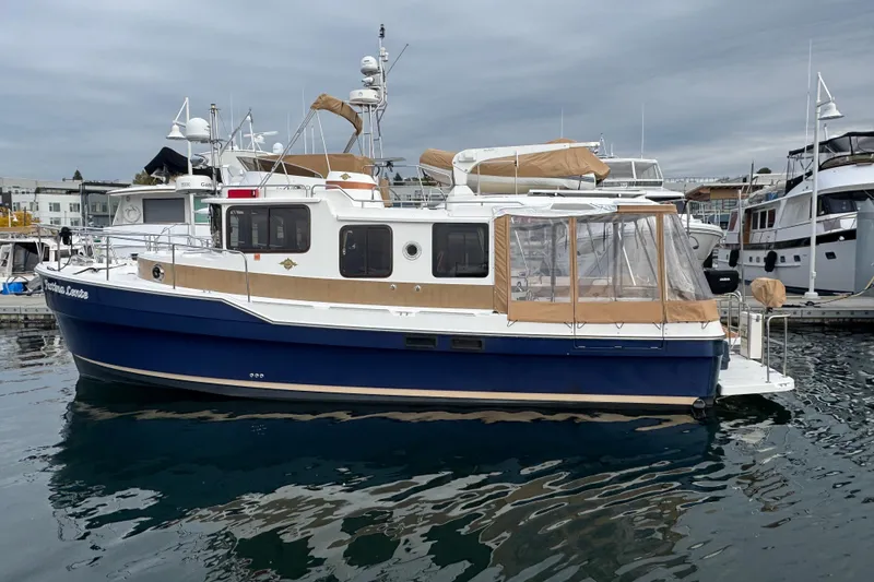Slide: The Image of 2019 Ranger Tugs R-31 S boat docked in marina, featuring blue hull and tan canopy. - 49
