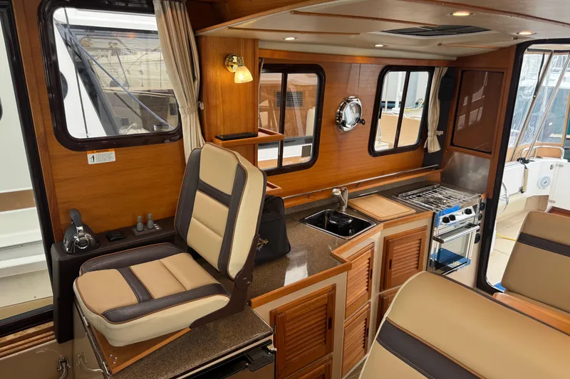 Slide: The Image of 2019 Ranger Tugs R-31 S interior with wood finish, kitchenette, and seating area. - 8