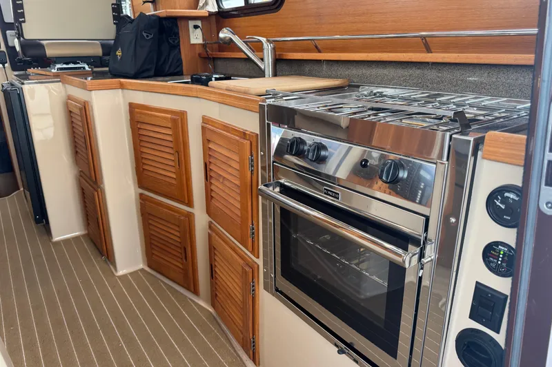 Slide: The Image of 2019 Ranger Tugs R-31 S interior kitchen with stove, wooden cabinets, and sink. - 9