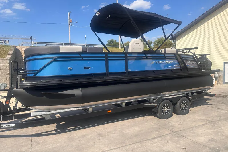 The Image of 2026 Starcraft CX 23 DL BAR pontoon boat on trailer, blue and black design. - 0