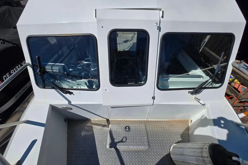 Slide: The Image of 2020 Raider 250 Sea Raider boat cockpit with windshield and wipers, featuring diamond plate flooring. - 26
