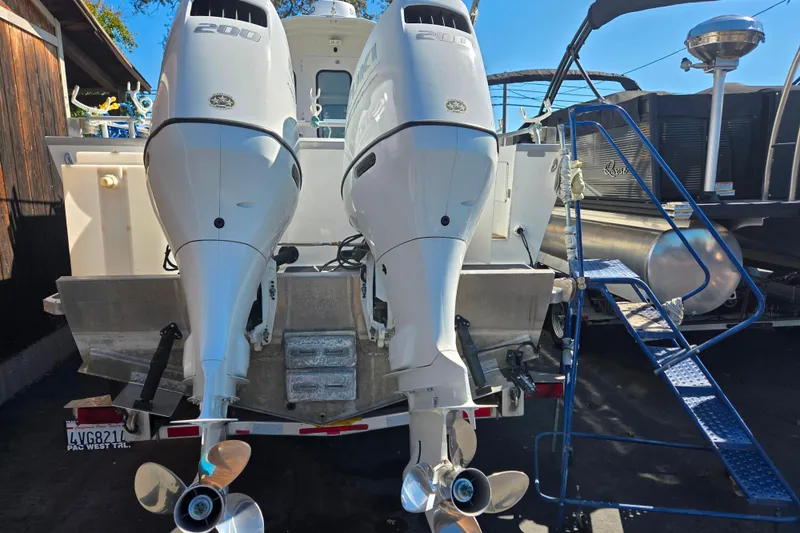 Slide: The Image of 2020 Raider 250 Sea Raider with dual outboard motors, docked beside a pontoon boat. - 4