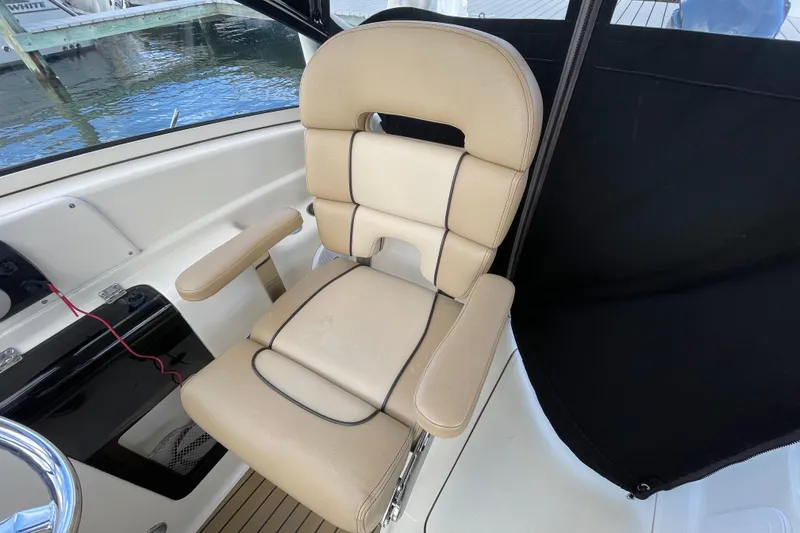 Slide: The Image of Captain's chair on 2015 Scout 245 Dorado boat, beige upholstery, near water. - 18